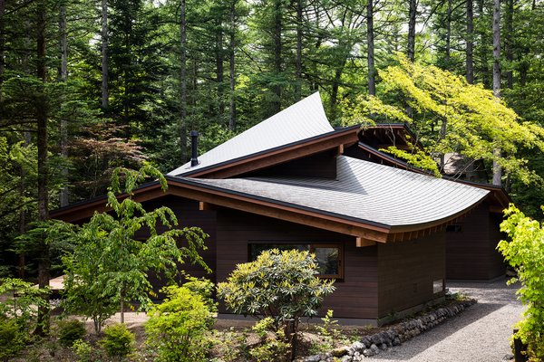 The roofs’ concave and convex forms are elegantly layered and integrated into the home's forested setting.