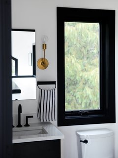 The bathroom features an Astrid Sconce with a natural brass finish from Schoolhouse. 