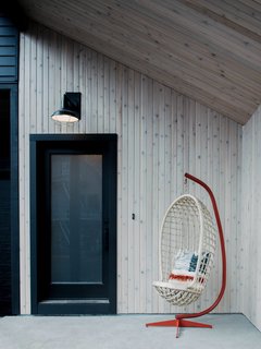 The exterior paint is a custom-blended black that Keasler requested. "I wanted a color that was a little more faded since the chalet has such a modern silhouette. I felt that a true black would be too stark," she explains. The black contrasts with the whitewashed cedar front porch, which features a Factory Light 4 Outdoor Sconce from Schoolhouse and a vintage chair. 