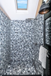 The luxury bathroom boasts a stylish glass-tiled shower and a solar-vented skylight.