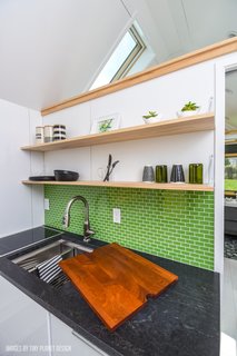 The kitchen has an induction cooktop from Jenn-Air, a work station sink, and a dark granite countertop.