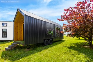 The Roost26 tiny house features a lightweight, black AG metal roof and facade with a "detachable garden" on one side and bike racks on the other. 