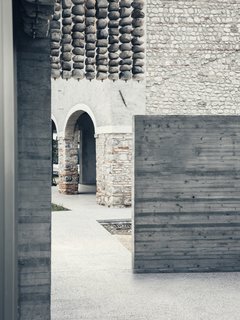 The preserved stone walls and arched portico of the main residence, as viewed from the guest house.