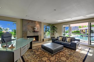 The master suite also includes a sitting area with a fireplace and sliding doors leading out to the pool area.