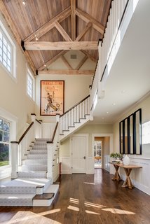 Stairs lead from the entry to the upper level with the bedrooms. The wood-paneled, vaulted ceiling adds warmth to the double-height space. 