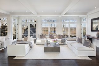 The light-filled living room in the main house has full-height windows showcasing views of the Croton reservoir. 