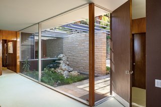 Beyond the stone wall and slatted wood siding, the home features over 4,000 square feet of living space carefully carved into the hillside. The glazed entry leads to an expansive open plan living space. 