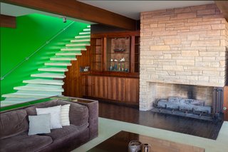 The lower level features an additional living room with a cozy inlaid stone fireplace and a view of the pool. 