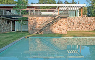 Inside and out, the home displays a rich mix of natural materials. A stairway cantilevers from the fieldstone wall and leads to the pool.