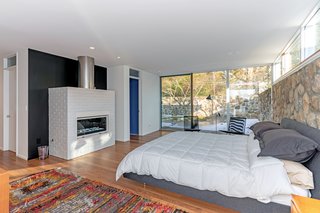 The master bedroom is located in its own wing, and it features a cozy gas fireplace and its own terrace. An inlaid stone wall runs from the exterior terrace into the space, establishing a strong connection with the outdoors. 