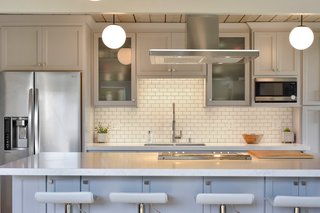 The kitchen has been updated with quartz countertops, designer appliances, and an island with breakfast bar seating. 