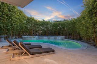 The kidney-shaped swimming pool is shaded and private. There is also an outdoor shower area. 