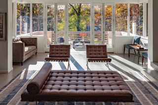 The living room connects to the deck. Full-height windows with butt-glass corners provide tree-filled views. 