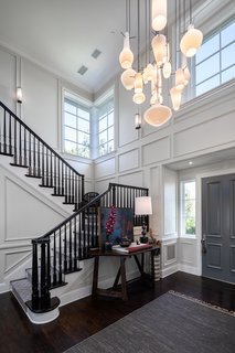 The garden walkway leads to a double-height entry hall with a contemporary chandelier composed of pendant lights of varying shapes.