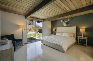 The master suite features direct access to the outdoor space via sliding glass doors. There is also an ensuite bath with updated fixtures and original cabinetry.