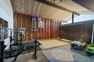 The flexible, wood-paneled garage space is currently in use as a home gym and a play area. 