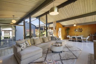 The open-plan great room has an unpainted, vaulted, tongue-and-groove ceiling and original globe pendant lighting.