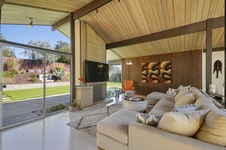 The expansive wall of glass is broken by the brick-inlay, wood-burning fireplace, a signature Eichler feature. 
