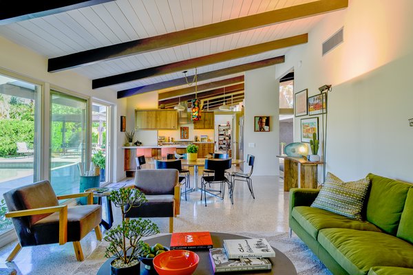 The bright and airy, open-plan layout includes the dining area, living area, and kitchen. Sliding glass doors open to the outdoor terrace and swimming pool.