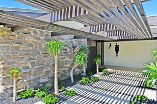 A wooden pergola shades the entrance to the home. 
