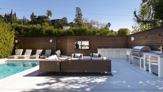The pool and spa area features a fire pit, a built-in grill, beer on tap, an ice maker, and even an outdoor sink and fridge.