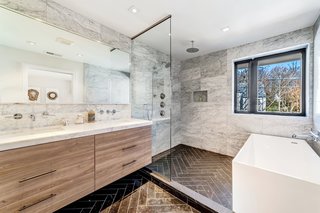 &nbsp;The en suite master bath features luxe marble-clad surfaces that include Carrera marble countertops and Piatra gray herringbone marble floors. There is also a deep soaking tub.