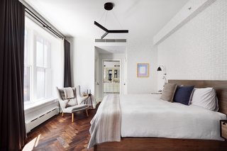 The bright and airy master suite features wallpaper from Maharam-System.