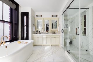 Roman & Williams designed the bathrooms with "the look and feel of a grand European hotel". The double vanity is painted a high-gloss cream and slabs of Calacatta marble is mixed with brass fixtures makes the master bath shine.