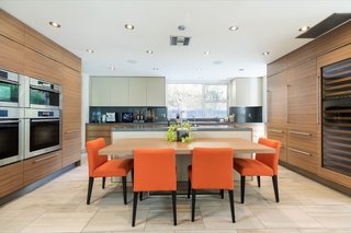 The open kitchen features warm wood paneling, a center island, and a deluxe wine fridge.&nbsp;