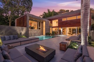 The backyard has a zero-edge swimming pool and a spacious lounge area with a fire pit. There's also a high privacy wall topped by a perfectly manicured privacy hedge.