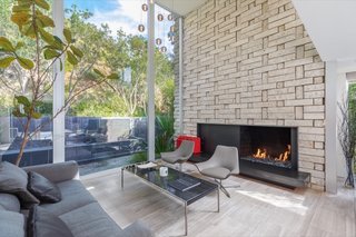 The living space features walls of glass that overlook a serene garden patio and full-height glass sliding doors open the living room to the front yard for true indoor/outdoor living.&nbsp;