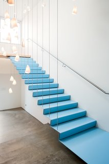Floating stairs to the boardroom are framed by over forty porcelain 21 series pendants by Bocci.