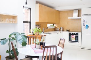 The open-plan kitchen is modernized with birch plywood cabinets, corian countertops and space-efficient appliances.