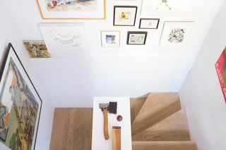 The whitewashed oak staircase, flanked with a salon-style art display.