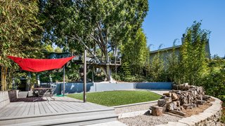 The backyard features a treehouse, wrapped around a robust ficus tree, and a rope swing over a grassy lawn.