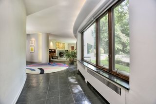 A Curvaceous Connecticut Home Asks $2.6M - Photo 3 of 8 - A meandering corridor connects the dining room and living room. Labatut notes that "the absence of parallelism between walls and the absence of doors gives a great fluidity and value to space, yet privacy is insured...by the curving and treatment of walls." 