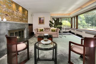 A Curvaceous Connecticut Home Asks $2.6M - Photo 5 of 8 - The living room's fieldstone and aluminum fireplace includes a hidden wood bin that is accessible from outside, keeping the homeowner supplied throughout winter.
