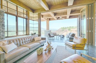 Tall glass walls fold back to allow an uninterrupted flow of space between the living room and the patio.