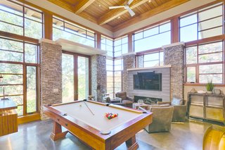 From the living room, thick oak stair treads suspended on steel stringers descend to the game room, where a walnut bar, Craftsman pool table, and fireplace set the scene for entertaining and lounging.