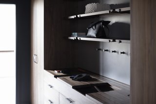 The Wardrobe System features sliding wooden valet trays, leather lined storage compartments, custom interior felt door pockets, handcrafted leather pulls, and an integrated laundry hamper.