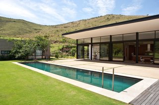 The pool stretches across a rolling lawn that ends at the foot of the wooded mountains.
