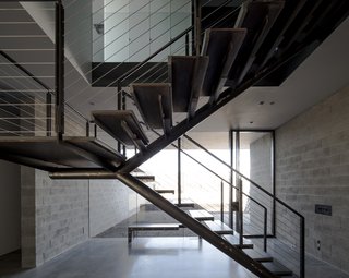 The staircase remains open in form, helping to visually knit the entryway's garden into the living space while providing a structural focus.