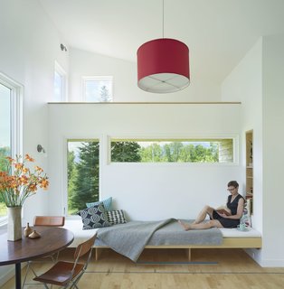 A pine interior subtly frames each window opening to accentuate views without obstructing them. The light material palette in the home contributes to a sense of airiness. Local maple planks on the floor have been cut to shorter lengths and laid perpendicular to the view, giving it a fluid effect. A camouflaged hatch door leads to the basement level, which acts as a storage and laundry area. 