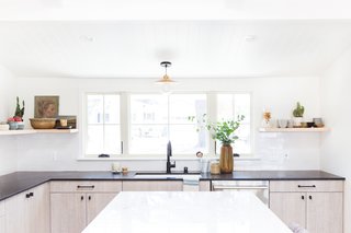 A white undermount sink and a matte black faucet are functional, refined elements. "The one thing I did love about the previous kitchen was the large window over the sink, and that's the only design element we chose to keep," says Lewis.