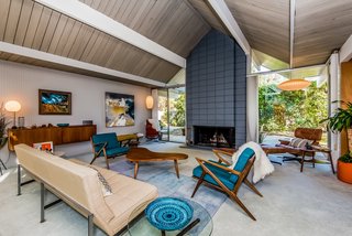The Cigar and Saucer Pendant Lamps by George Nelson and the 3-seat sofa and wall-mounted cabinet by Knoll are original—and also available for purchase. A cinderblock fireplace provides an inviting focal point.