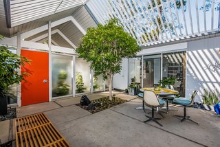 A covered entrance doubling as a carport leads to the square atrium, where cutouts in the concrete allow greenery to establish a sense of the outdoors. Enclosed in glass on all four sides, the atrium opens to the living room, multipurpose room, office and retreat.