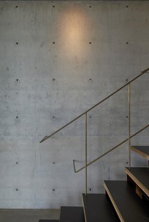 9 Unique Stair Railings - Photo 9 of 9 - The slim brass rods of the stair railing in this countryside house in Australia create a shimmering silhouette against the matte texture of the concrete wall. The rods die gracefully into the wall of the concrete, and the notes of brass are picked up by the concrete plugs inserted into the panels.