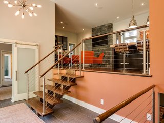 "My favorite feature is the entry of the home," says Finein. "It is where you see the greatest transformation, both inside and out." Hickory floating stairs and a stainless steel railing system lead to the upper floor. Through the frosted glass barn door is the office, which enjoys a granite countertop built-in desk. 