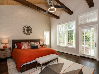 Three exposed beams run across the vaulted cedar ceiling in the master bedroom, which has private access to the back deck. The generous closet features custom built-in wood shelving and a packing island with a granite top. 