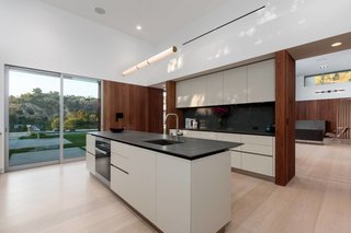 Boffi kitchen cabinets are a minimalist complement to Miele appliances, including a wine fridge and a built-in expresso machine. The Mini Endless pendant is by Roll & Hill.